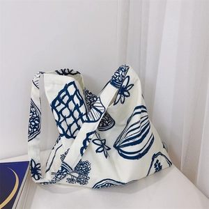 Détail du cabas en toile blanche avec motifs floraux bleu foncé peints à la main sur fond blanc