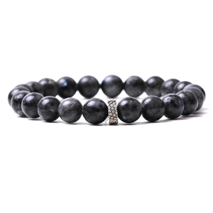 Macro detail of natural dark grey stone beads with textured silver metal charm spacer