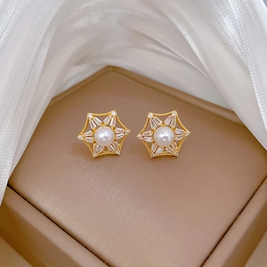 Macro shot of gold hexagon star earrings with white pearl and sparkling zircons
