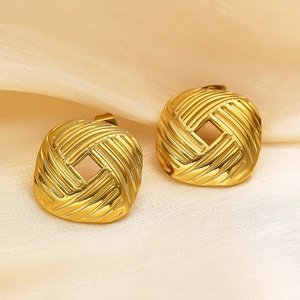 Détail macro de boucles d'oreilles carrées dorées avec surface métallique rayée
