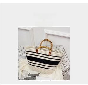 Detail of woven tote bag with bamboo handles and black and white stripes inside a basket