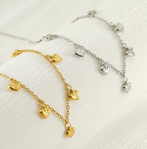 Detail view of gold and silver heart necklaces on textured white fabric