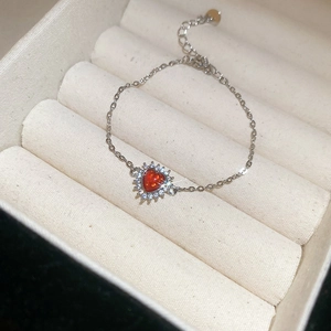 Detail of red heart zircon pendant bracelet on a beige velvet jewelry box tray