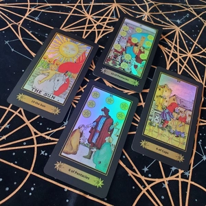 Detail of tarot cards with gold foil patterns featuring The Sun and 10 of Pentacles