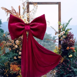 Oversized burgundy velvet bow with long streamers for outdoor wedding arch decoration