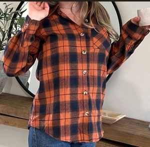Detail of classic plaid flannel shirt featuring orange and navy grid with wood-style buttons