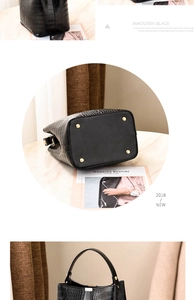 Detail view of black crocodile pattern bucket bag with golden protective base studs