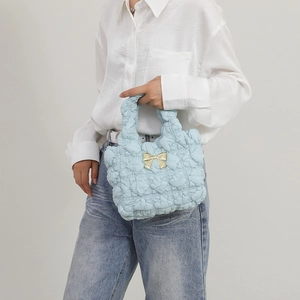Light blue bubble cloud bag with gold bow decoration, handheld by model in profile view