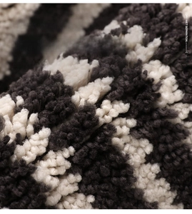 Detail showing thick plush fiber texture of black and white striped bath mat for dry-wet separation
