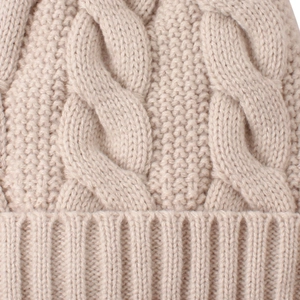 Detailed macro view of beige cable knit pattern and texture on a winter beanie hat