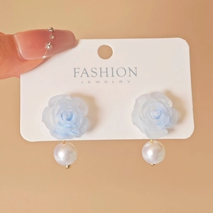 Detail of blue resin rose earrings with white pearls on a fashion jewelry card