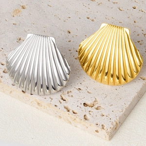 Detailed macro view of gold and silver shell-shaped 304 stainless steel rings on stone