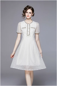 Close-up of geometric lace texture and elegant pearl button details on a French white dress