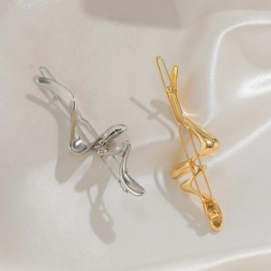 Detailed view of gold and silver irregular liquid metal wave hair clips on white silk