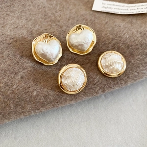 Dettaglio di orecchini a cuore e perle tonde placcati in oro 16K su tessuto marrone