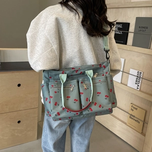 Women's sage green tote bag with cherry print and adjustable strap in a lifestyle setting