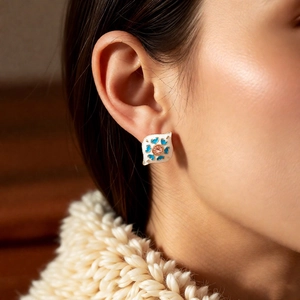 Close-up of vintage enamel earring with blue heart pattern and pink gemstone inlay