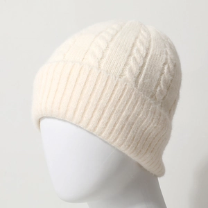 Close-up of cable knit texture and ribbed cuff on a cream-white winter beanie