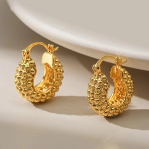Close-up of 18K gold-plated oval hoop earrings featuring a beaded granulated texture