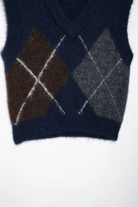 Detailansicht der weichen Stricktextur und des klassischen Rautenmusters auf der Weste