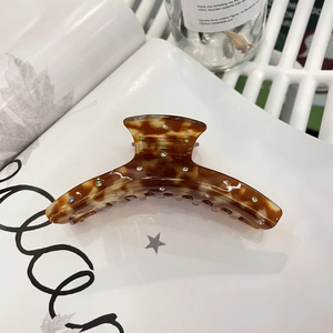 Amber acetate hair claw clip with colorful rhinestones on an artistic magazine