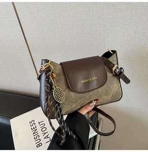 Detail of vintage matte crossbody bag with gold tennis racket charm and tassel
