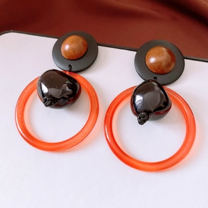 Detailed close-up of retro geometric earrings with orange resin hoops and wooden beads