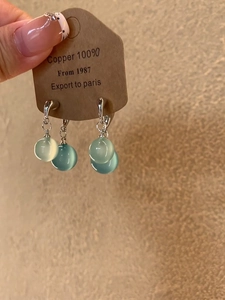 Detail of silver drop earrings with teal resin beads on a brown craft card