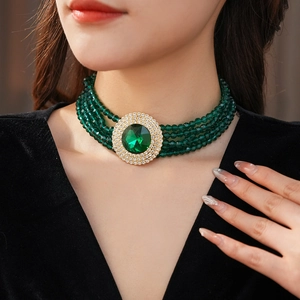 Detail of luxury emerald green beaded necklace with gold-rimmed centerpiece on a model