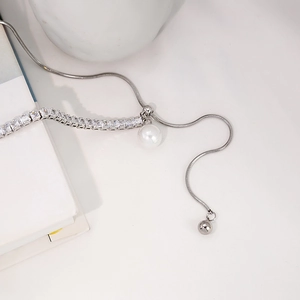Detail view of silver snake chain necklace with square zircon and white pearl pendant
