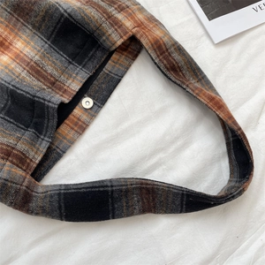 Detail of silver magnetic buckle closure on a brown plaid wool shoulder tote bag