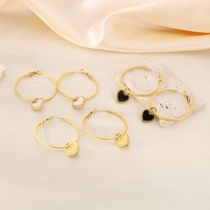 Detail of heart hoop earrings in gold with black and white enamel finishes on silk