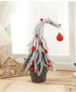 Detail of a mini snowy Christmas tree with red berries and a sparkling red ball ornament