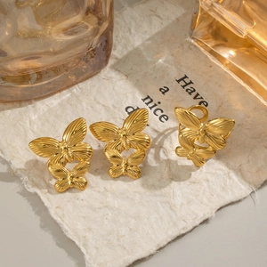 Three golden 18K butterfly rings set on vintage paper background with soft warm lighting