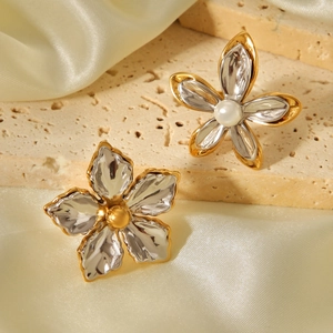 Detailed shot of two-tone flower earrings with pearls on silk and stone backdrop