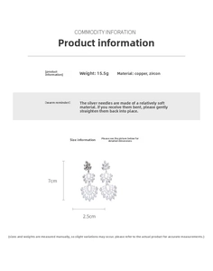 Détail de boucles d'oreilles pendantes en cuivre poli avec zircons en forme de feuille