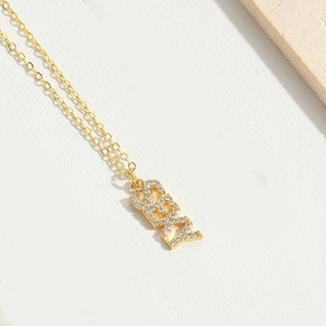 Detailed view of a gold chain necklace with a sparkling rhinestone SEXY letter pendant
