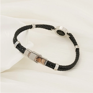 Detail of woven black leather bracelet with silver anchor star charm and magnetic clasp