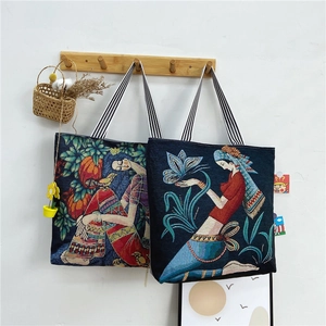 Ethnic jacquard tote bag with artistic patterns and striped shoulder straps on white wall