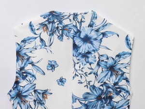 Détail de l'imprimé floral bleu et des coutures de qualité sur le tissu tissé blanc