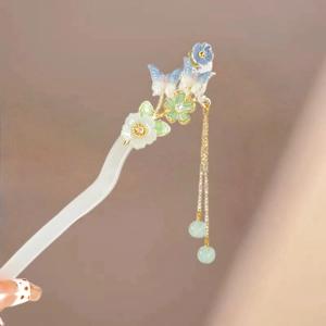 Detail of acetate flower hair stick with blue butterfly and long green tassel