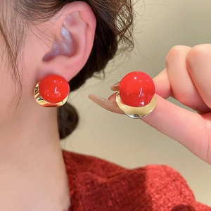 Detail of red spherical earrings with gold curved metal base on a female model