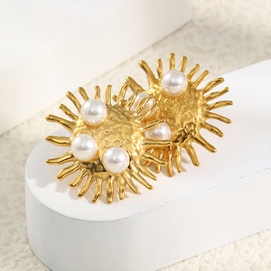 Close-up of vintage golden sunburst earrings with pearl accents on a white display