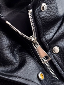Detailed close-up of premium black leather texture with silver metal zipper and snap button