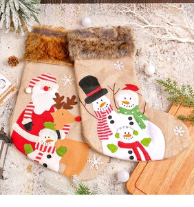 Detailed plush Christmas stockings with Santa and reindeer embroidery on linen texture