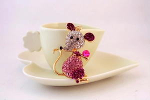 Close-up of golden mouse brooch with pink rhinestones and a pearl accent detail