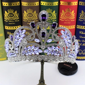 Detail of silver bridal crown with purple and clear crystals on a decorative base