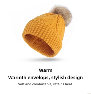 Close-up of yellow chunky knit beanie with ribbed cuff and fluffy faux fur pompom