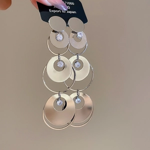 Detail view of tiered silver hoop earrings with clear zircon crystals in a layered design