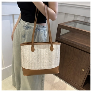 Lifestyle shot showing the large capacity woven straw tote bag with brown leather accents